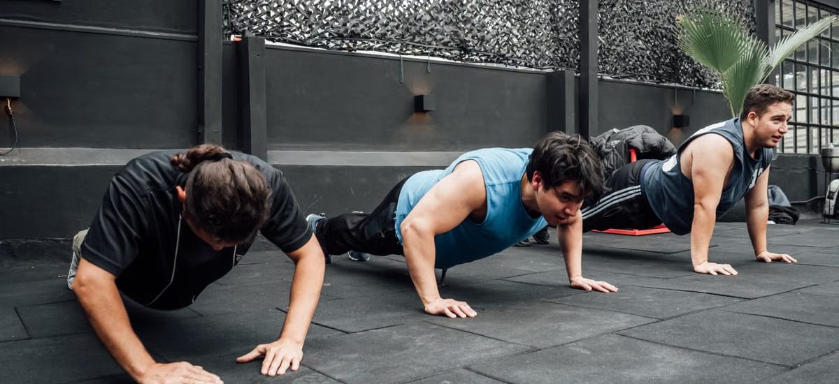 Men performing push-ups during a group workout session in Mexico City gym.